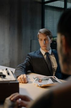 A tense interrogation scene with a detective and suspect in a dimly lit room.