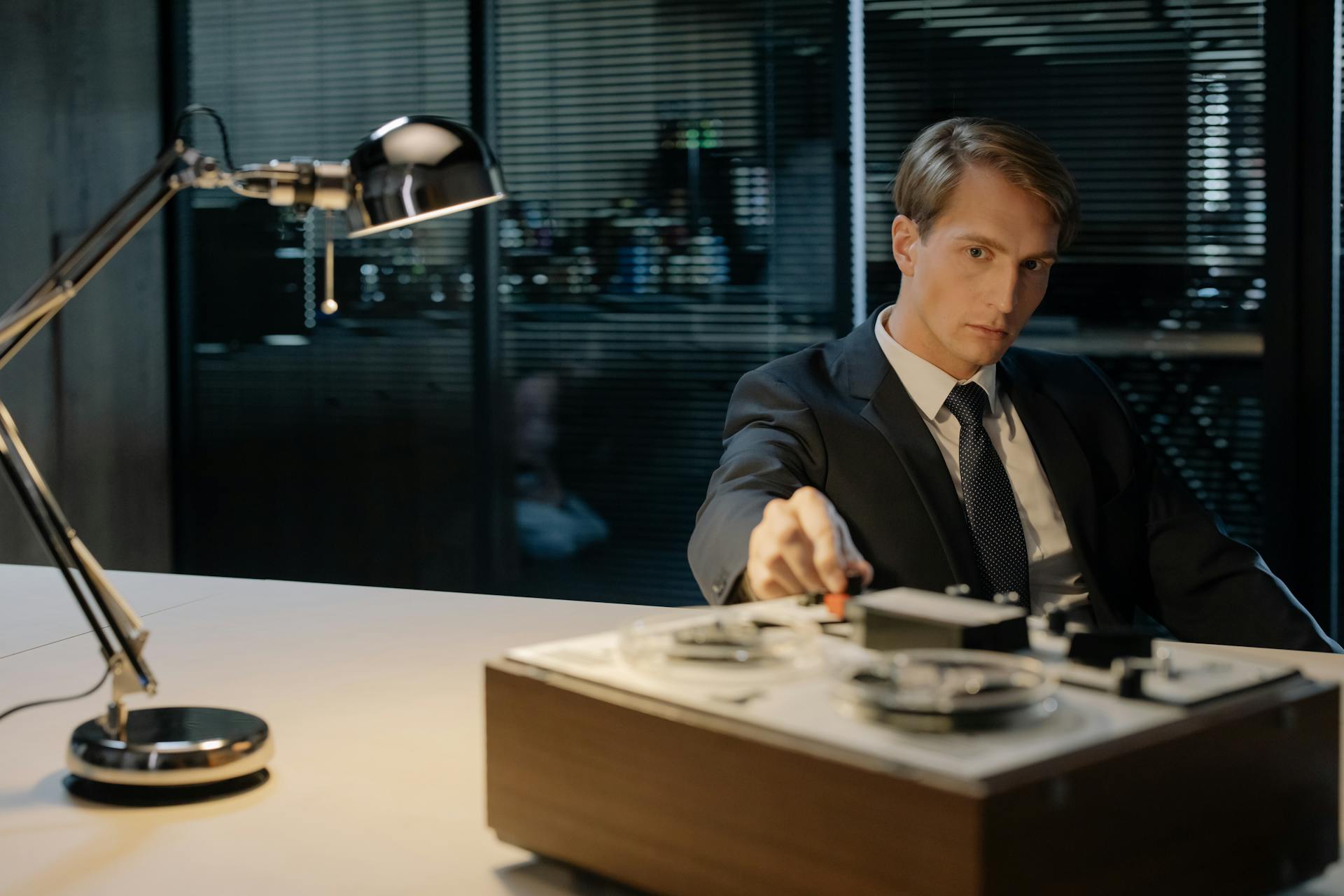 Detective Sitting at the Desk with a Reel-to-reel Audio Tape Recorder