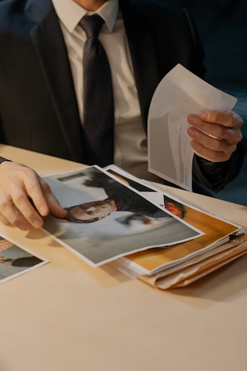 Close-up of a Detective Looking at Evidence on the Desk 