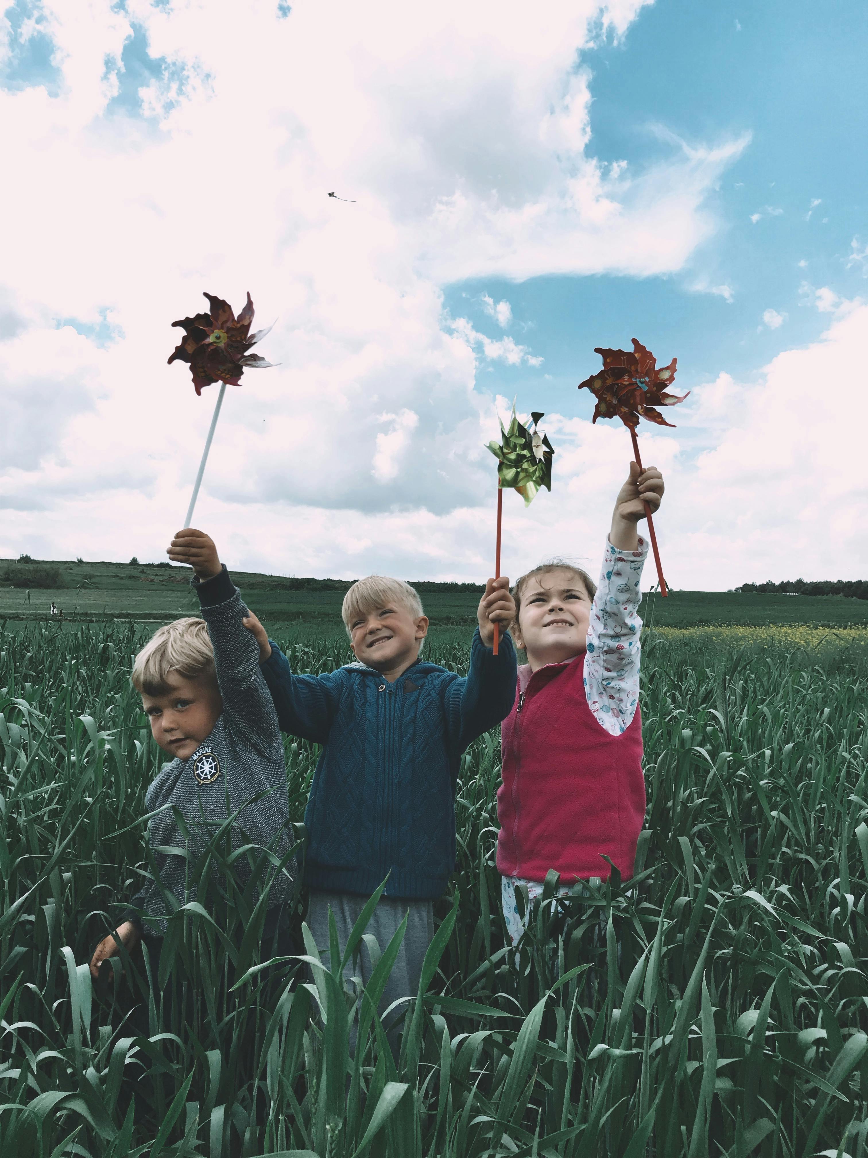 children playing with pinwheels in a cropland