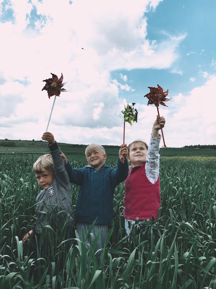 Children Playing With Pinwheels In A Cropland