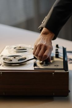 Close-up of a hand adjusting a vintage reel-to-reel tape recorder indoors.