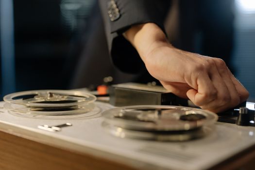 A close-up shot of a hand adjusting controls on a vintage reel-to-reel tape recorder.