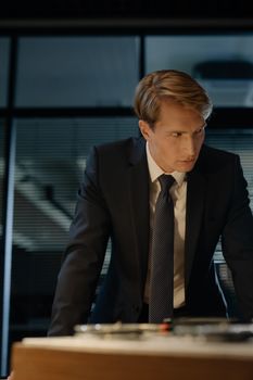 Professional man in suit leaning over a desk in a modern office setting.