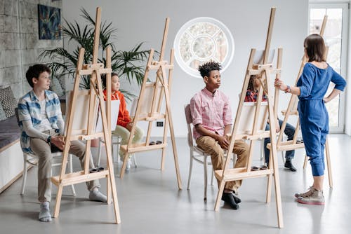 Teacher Talking to Students Sitting behind the Easels at an Art Class 