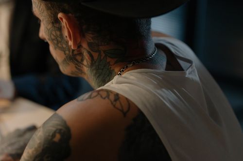 Free Close-up of a tattooed man in a tank top indoors, showcasing intricate body art. Stock Photo