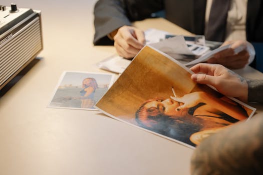 Two people examining printed photographs on a desk, implying investigation or evidence review.