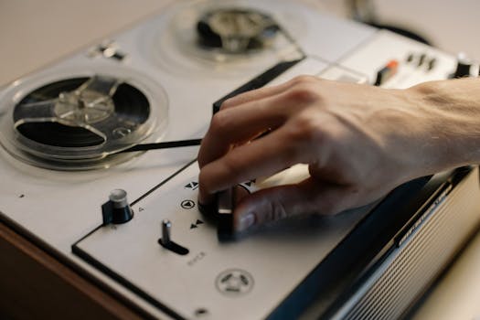 A detailed close-up of a hand adjusting controls on a vintage reel-to-reel tape recorder.