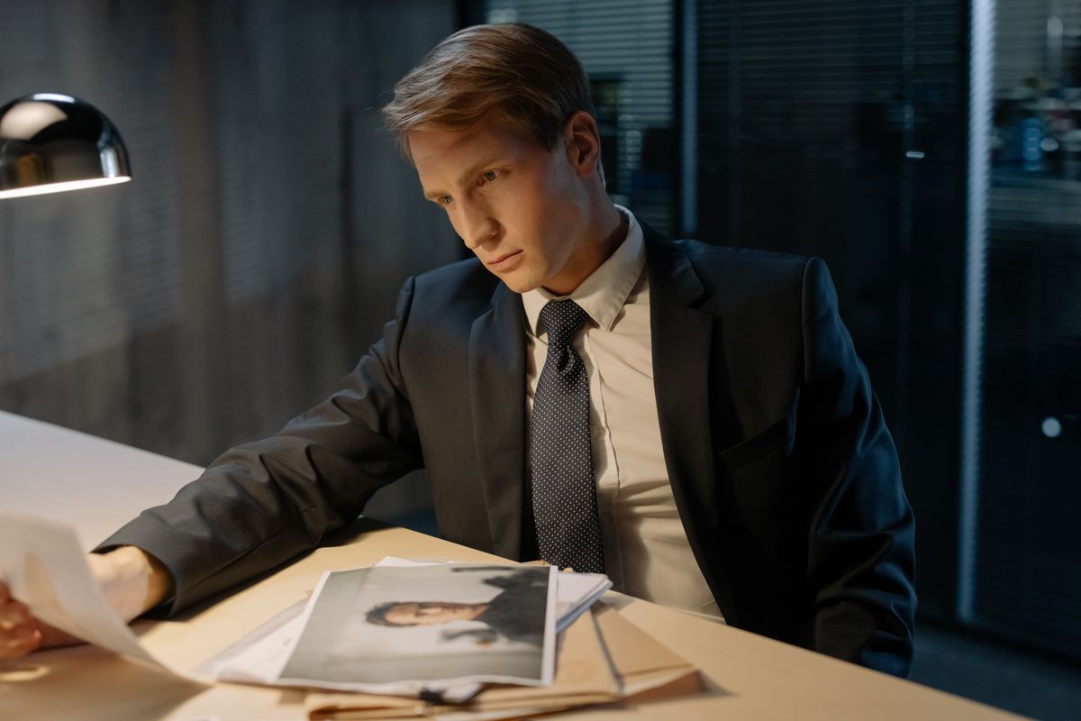 Investigator reviewing case documents under a desk lamp at night