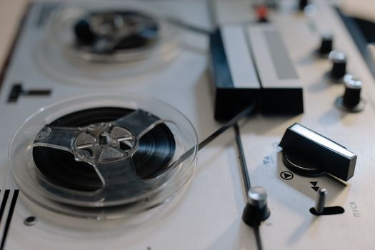 Close-up view of a classic reel-to-reel tape recorder with knobs and tapes.