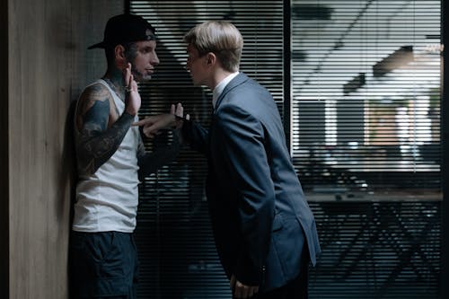 Free A Man in Suit Pushing a Man with Tattoo to the Wall Stock Photo