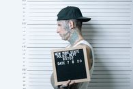 Man in Brown Hat Holding Black and White Quote Board