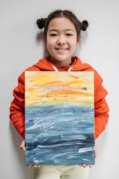 Young girl proudly displaying her vibrant painting. Perfect for creative art concepts.