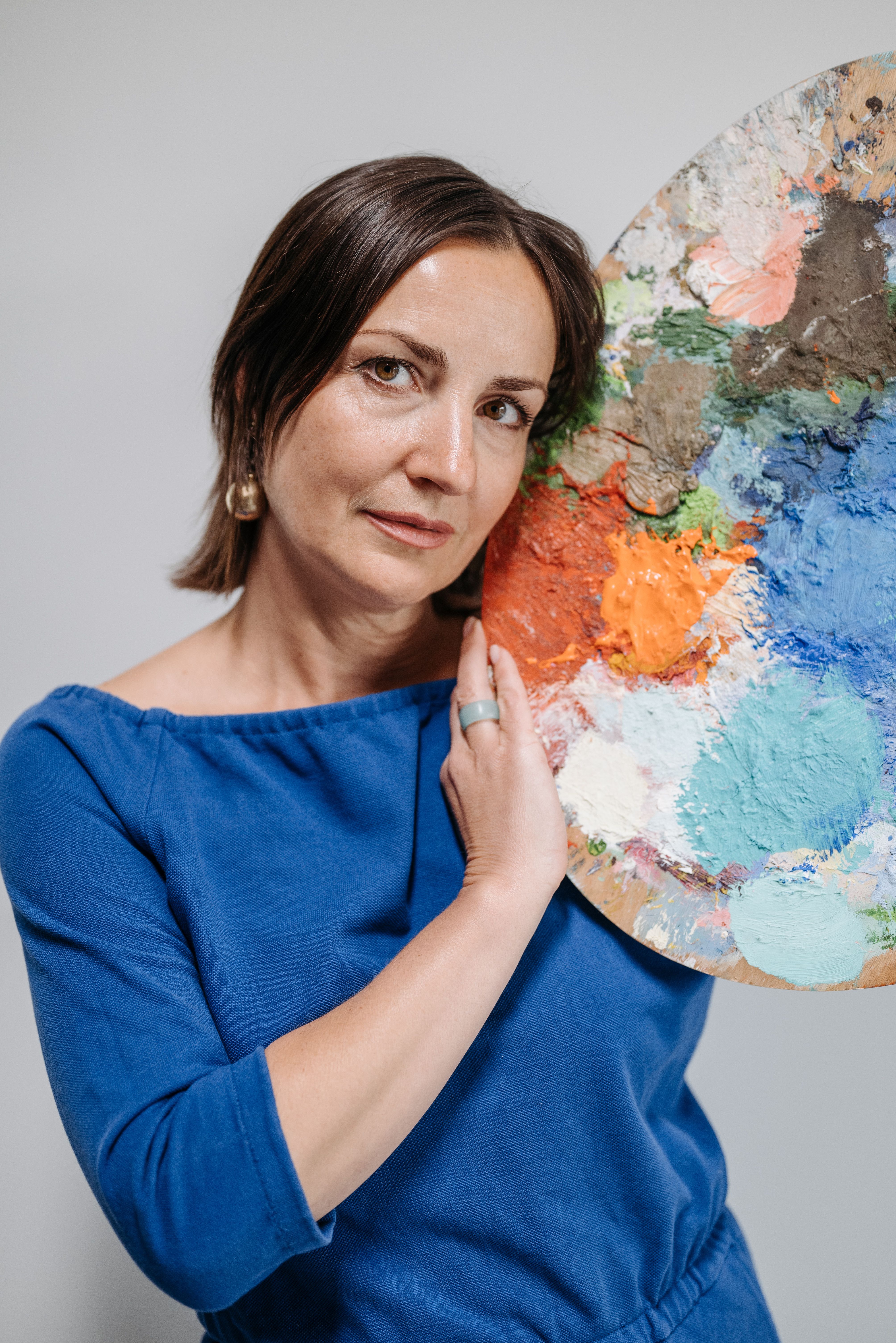 A female artist poses with a vibrant paint palette, showcasing creativity and artwork.
