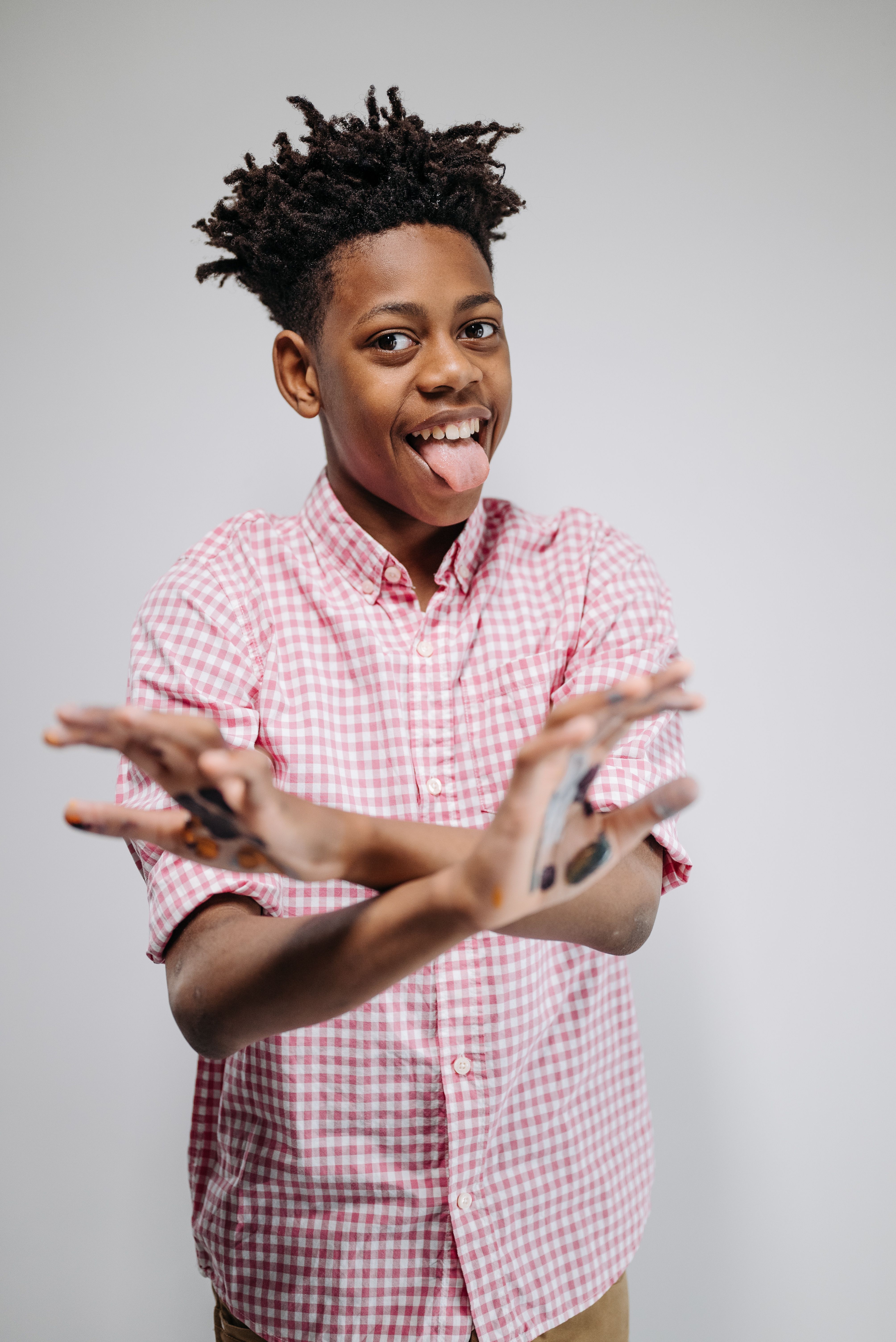 Energetic child with afro hair playfully posing against a plain background.
