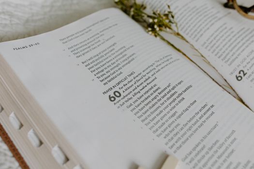 Close-up of an open Bible showing Psalm 60 with dried flowers.