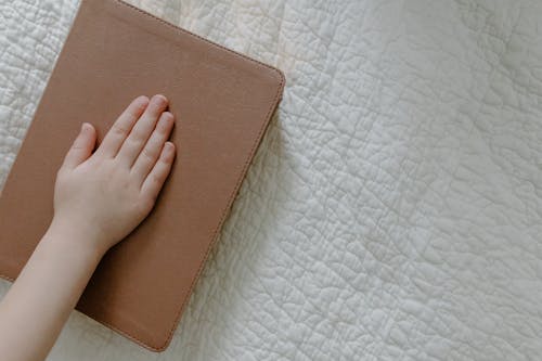 Hand of a Person on a Brown Book