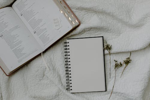 White Notebook Beside a Bible 