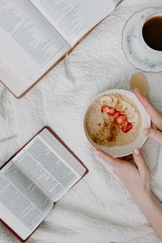 Flat lay of a cozy breakfast with oatmeal, books, and coffee. Perfect morning setup.