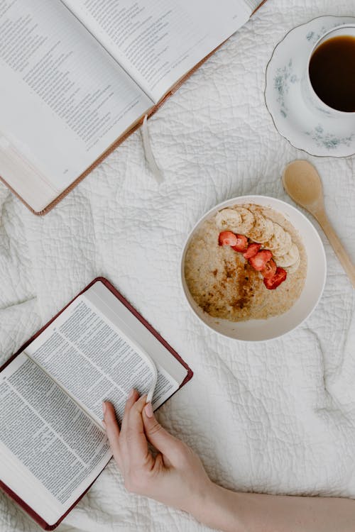 Free A Person Reading a Book While Having Cereal Stock Photo
