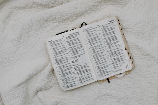 An overhead shot of an open Bible resting on a soft quilt, evoking a peaceful and contemplative atmosphere.
