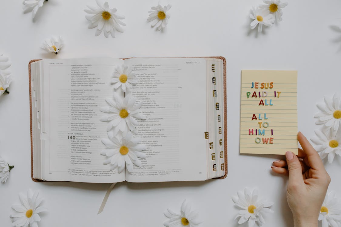 Free An Open Bible with Flowers and a Notepad Stock Photo