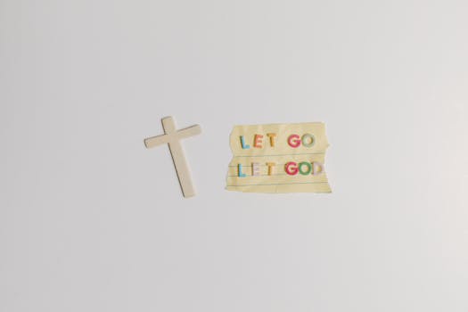 A simple and powerful image featuring a cross alongside the inspiring quote 'Let Go Let God' on paper.