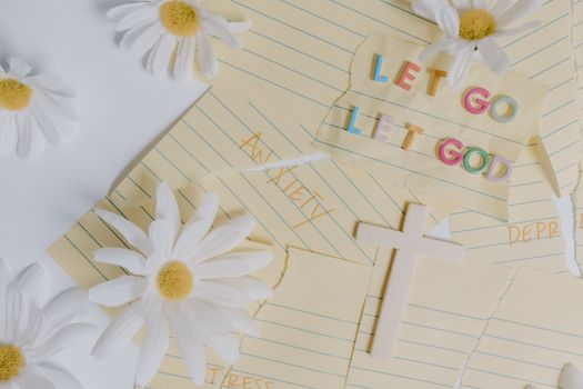 Uplifting flat lay featuring daisies, a cross, and the phrase 'Let Go, Let God'. Perfect for serenity and faith themes.