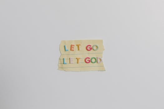 Minimalist image of a torn paper with the phrase 'Let Go, Let God' in colorful letters.