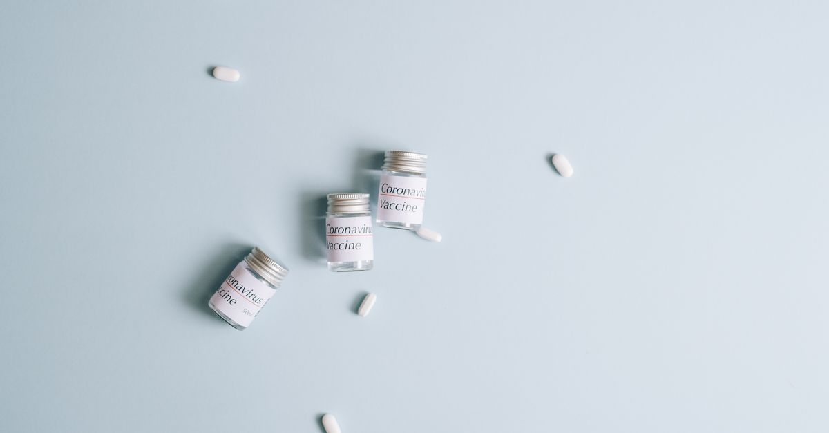 Three coronavirus vaccine vials with scattered pills on a light blue background, emphasizing healthcare and medicine. - Evidence evidence guide for lactoferrin immune support randomized trial