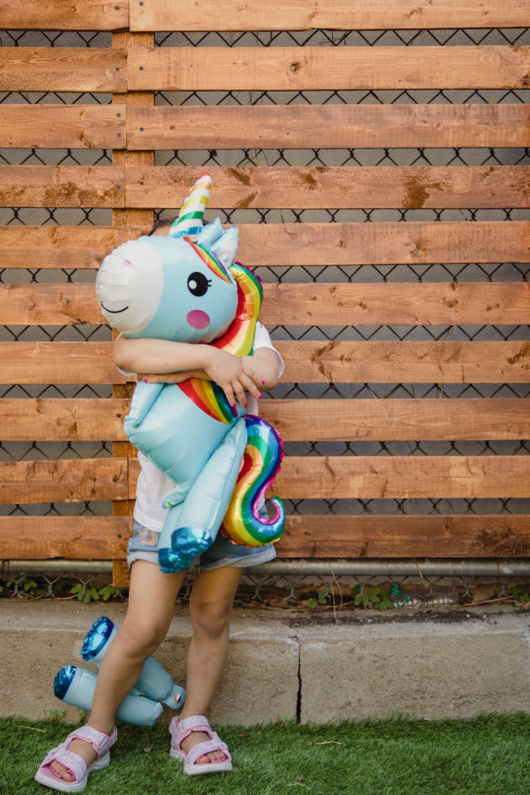 Girl Hugging A Unicorn Stuffed Toy