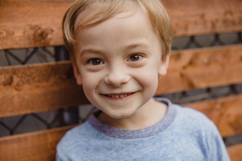 Free Close-up of a happy child with a wooden backdrop, exuding joy and innocence. Stock Photo