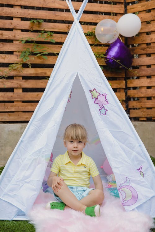 Free Girl in Yellow Polo Shirt Sitting inside the Tent Stock Photo