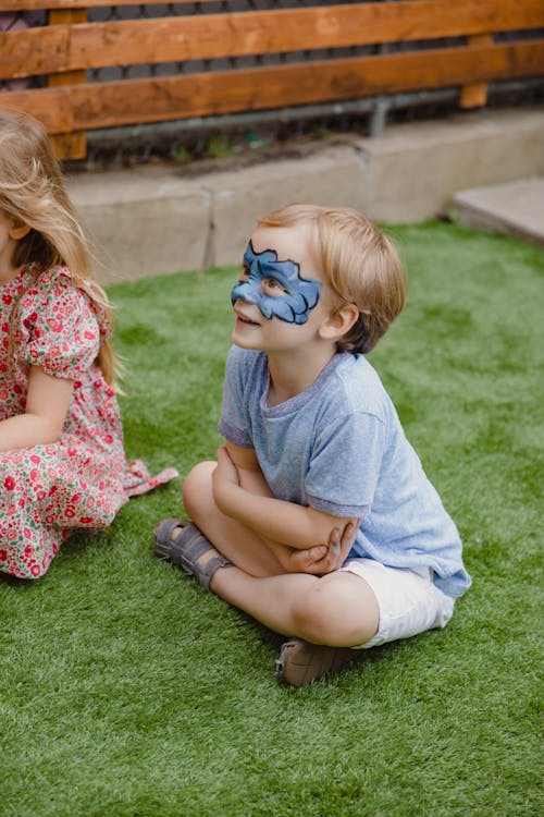 A Little Boy with Face Paint Sitting on the Ground