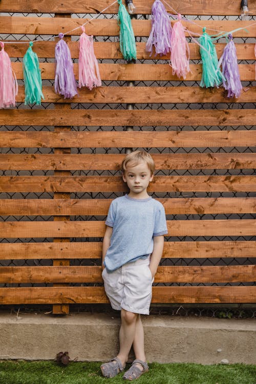 Young Boy Standing Against a Wooden Fence