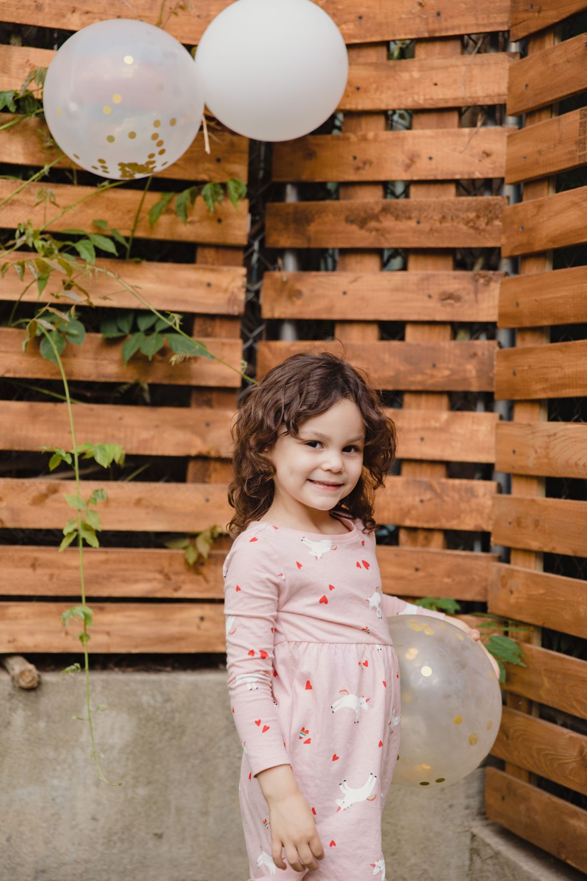 Smiling little girl in a unicorn print dress at a party for unicorn dress-up