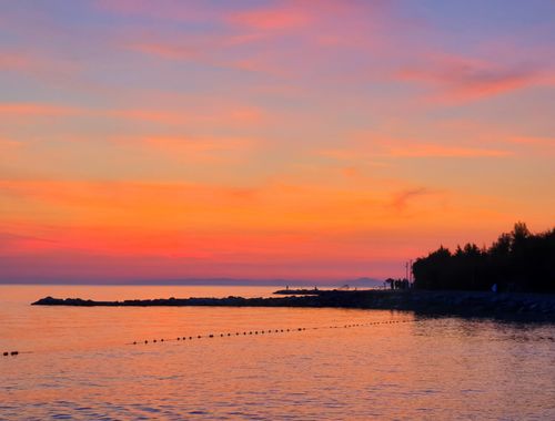 Free Beautiful sunset over a calm seashore with vibrant colors reflecting in the water. Stock Photo