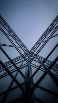 Dramatic low-angle shot of modern skyscraper glass facade reflecting sky.