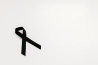 A black ribbon on a white background symbolizing mourning and remembrance, with ample copy space.