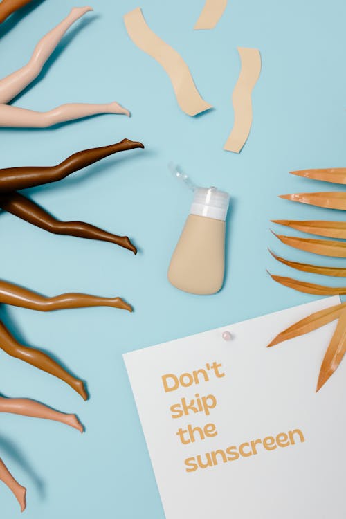 Free Paper with a Text Saying "Dont Skin the Sunscreen" Lying on Blue Background Stock Photo