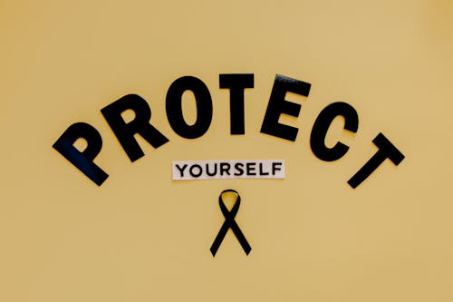 Free Text Saying "Protect Yourself" and a Skin Cancer Symbol - Black Ribbon - Lying on Brown Background  Stock Photo