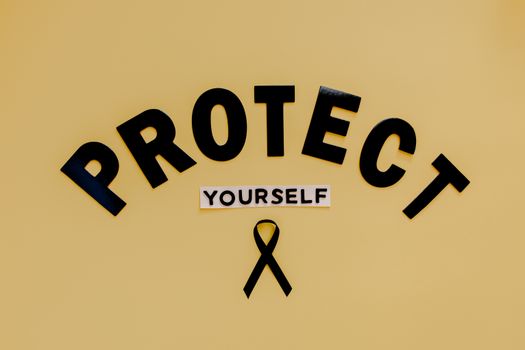 Conceptual awareness image with "Protect Yourself" text and black ribbon on yellow background.