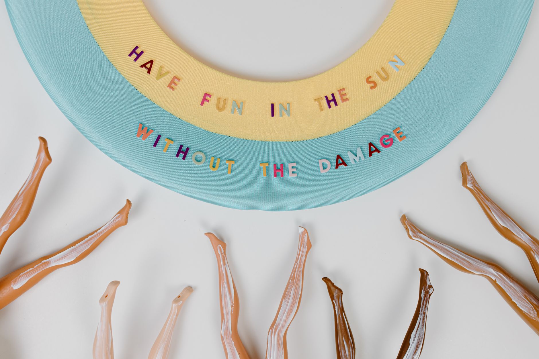 Conceptual image promoting sunscreen use, featuring doll legs and sun hat with fun text.