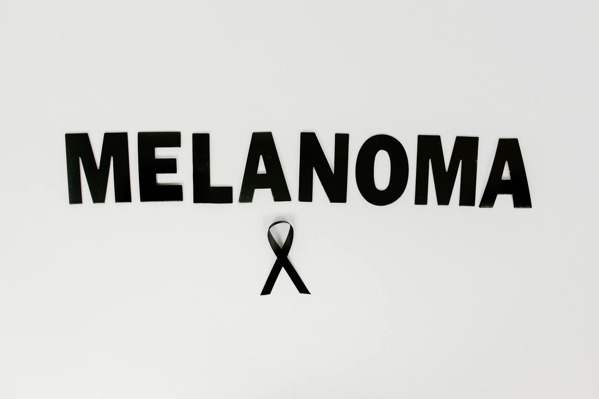 A Black Melanoma Text and Ribbon on White Surface