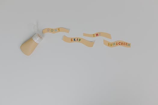 Sunscreen bottle and creative text 'Don't Skip the Sunscreen' on white background, promoting skincare and cancer prevention.