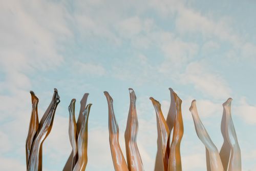 Free Creative display of mannequin legs reaching upward against a cloudy sky. Stock Photo
