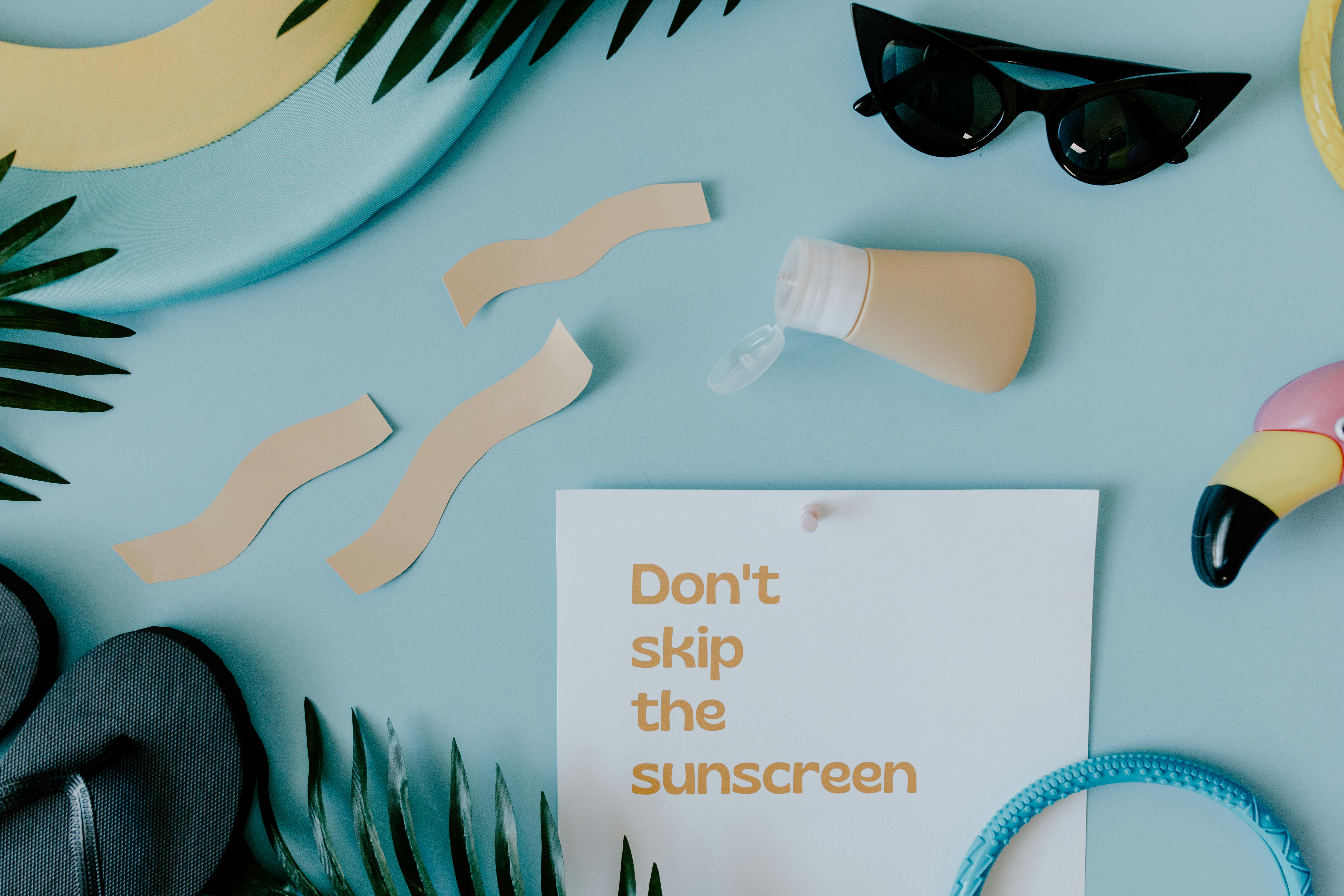 Flat lay of summer vacation essentials with a reminder to wear sunscreen.