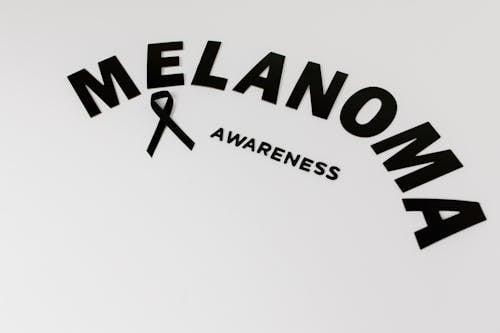 Free Black Text Saying "Melanoma Awareness" and a Black Ribbon Lying on White Background  Stock Photo