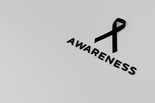 Minimalist image of a black ribbon symbolizing awareness against white background.