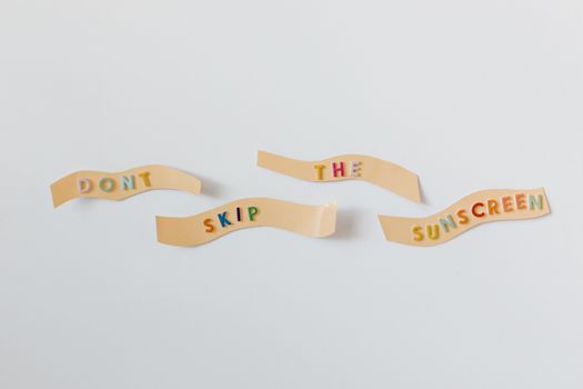 Colorful reminder to apply sunscreen with text on bandages on a white background.